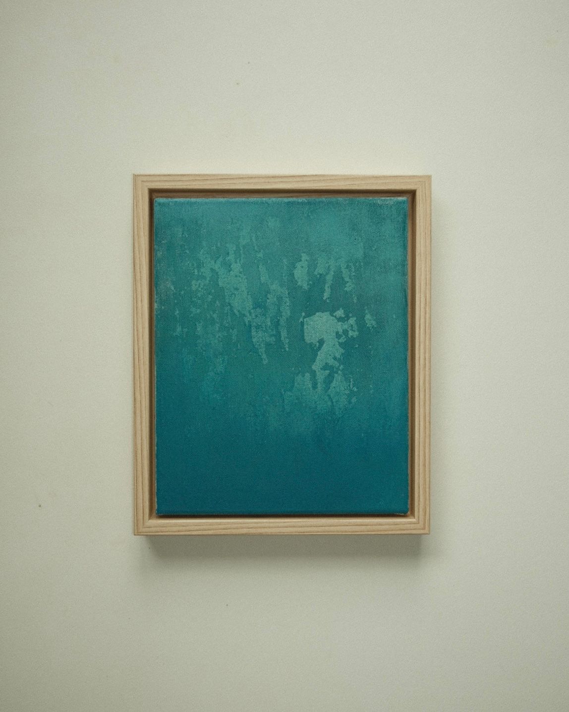 Small framed abstract in teal, with pale weathered patches near the top that settle into deep, even teal below.