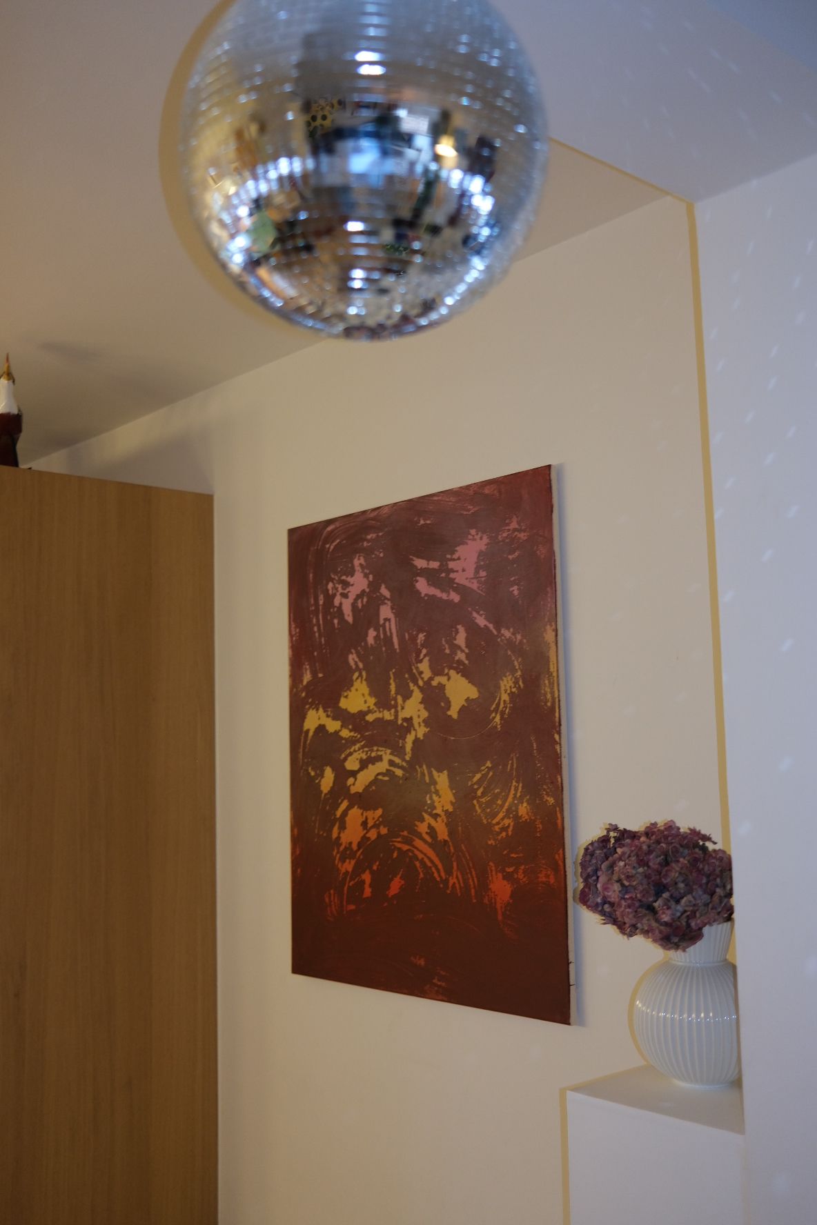 Abstract painting in portrait format. A dark plum and burgundy ground covered in sweeping circular strokes, with patches of pink near the top, ochre yellow across the middle and glowing orange towards the bottom. From an angle.