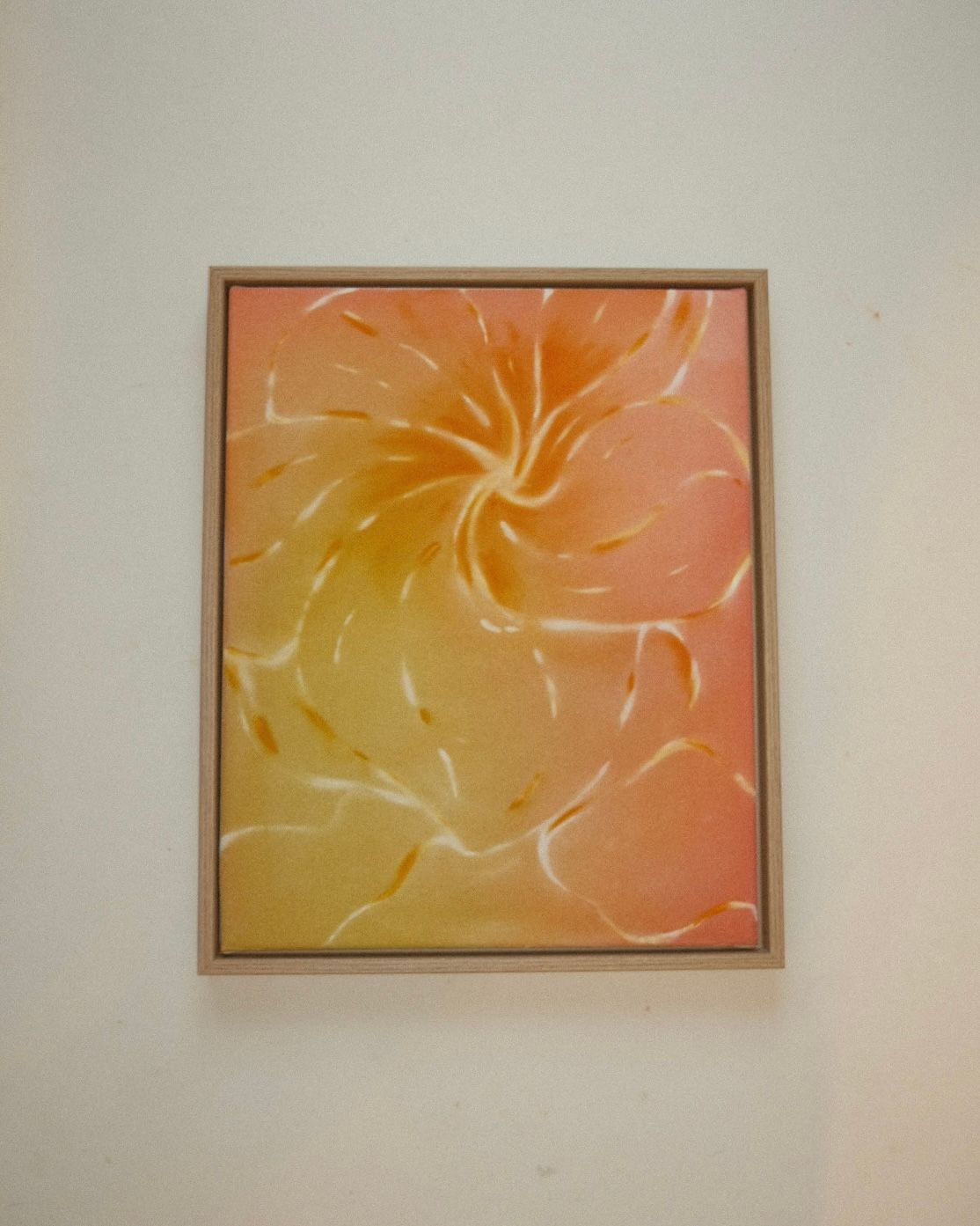 Close-up of frangipani petals spiralling out from the centre in peach, orange and yellow, with fine pale streaks.