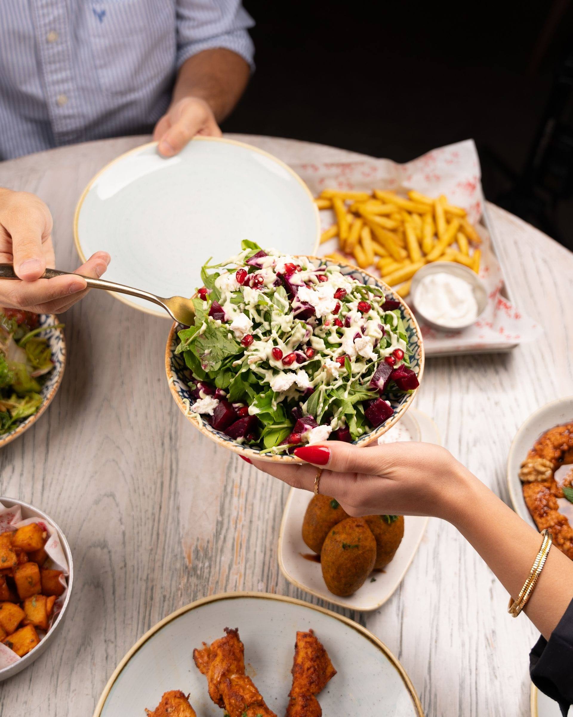Hands passing a dish across a table during a shared meal