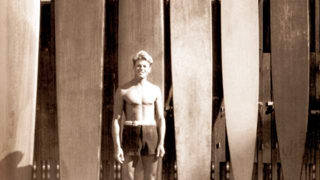 Tom Blake stands in front of his olo board; Waikiki, 1929.