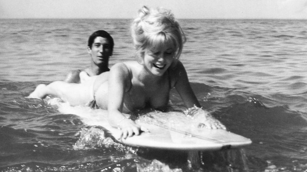 Joel de Rosnay gives a surf lesson to Catherine Deneuve, in Biarritz, 1962