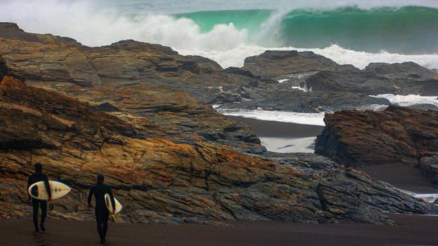 Surfers walking out to surf an island off Tierra del Fuego.