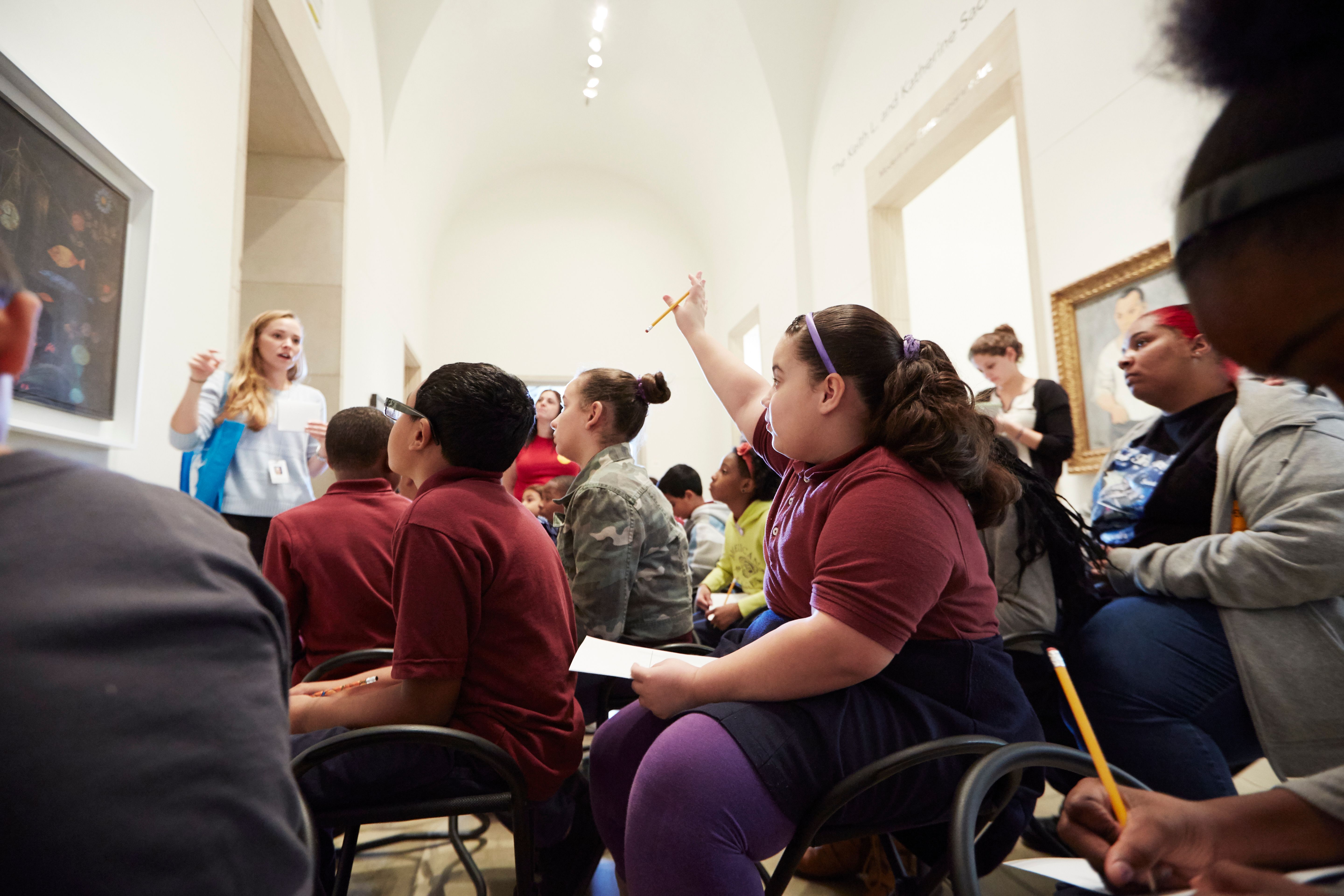 Student raising their hand during a workshop in a museum gallery