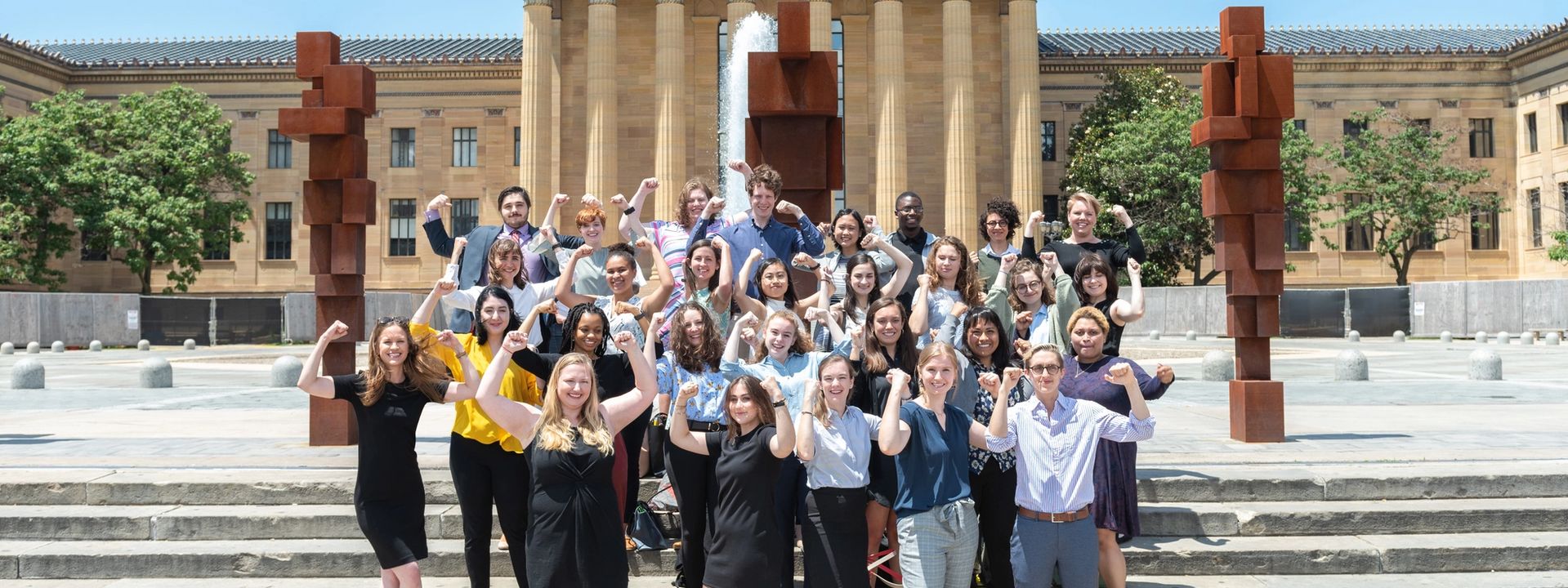 A group of interns doing the Rocky pose on the Rocky steps in front of the museum