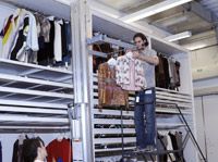 A hand cranked fork lift is used to raise hanging costume to the appropriate height for safe handling.