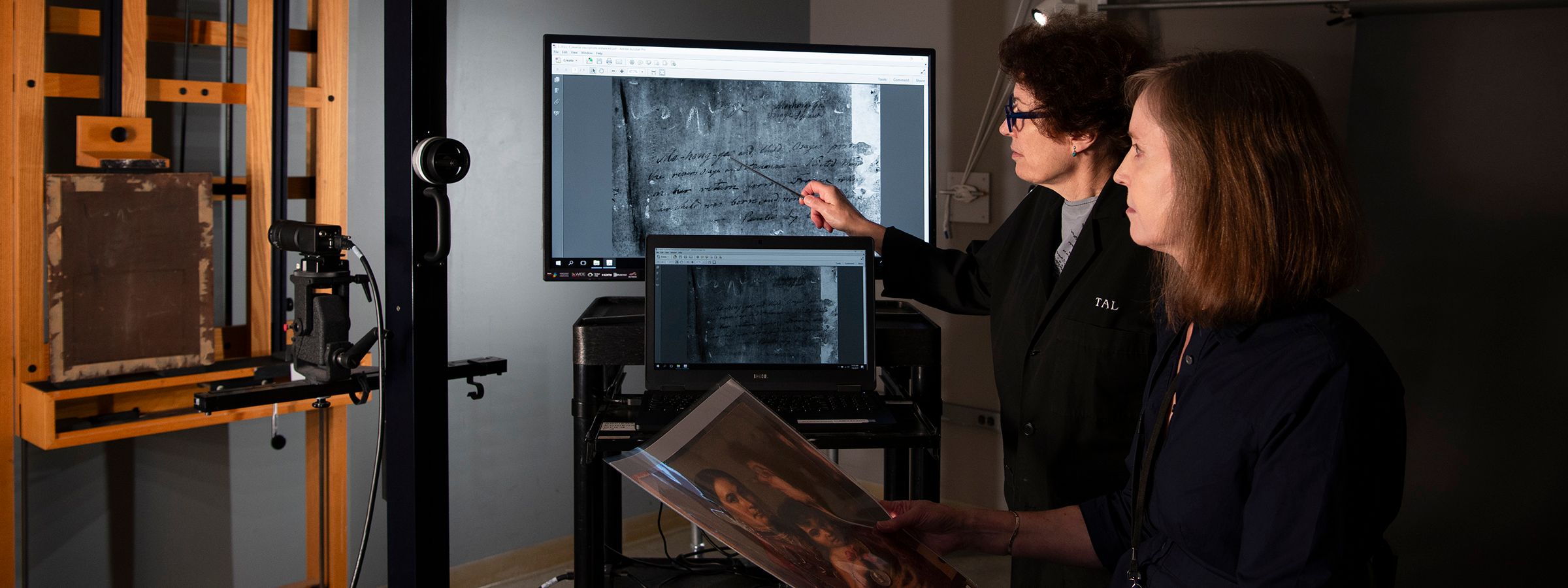 Two conservators examining scans of an object on a monitor.
