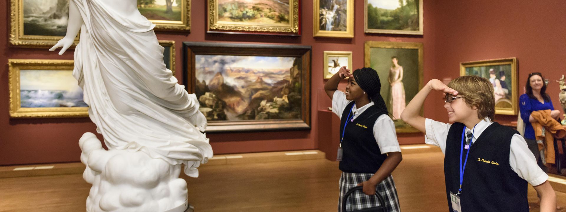 Two students on a tour in the galleries mimicking the body language of a statue