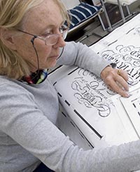 Marguerite Stephens annotating a hand-drawn cartoon of one of William Kentridge's <i>Puppet Drawings</i> in preparation for the weaving of a tapestry. Photo by John Hodgkiss, courtesy of William Kentridge Studio.
