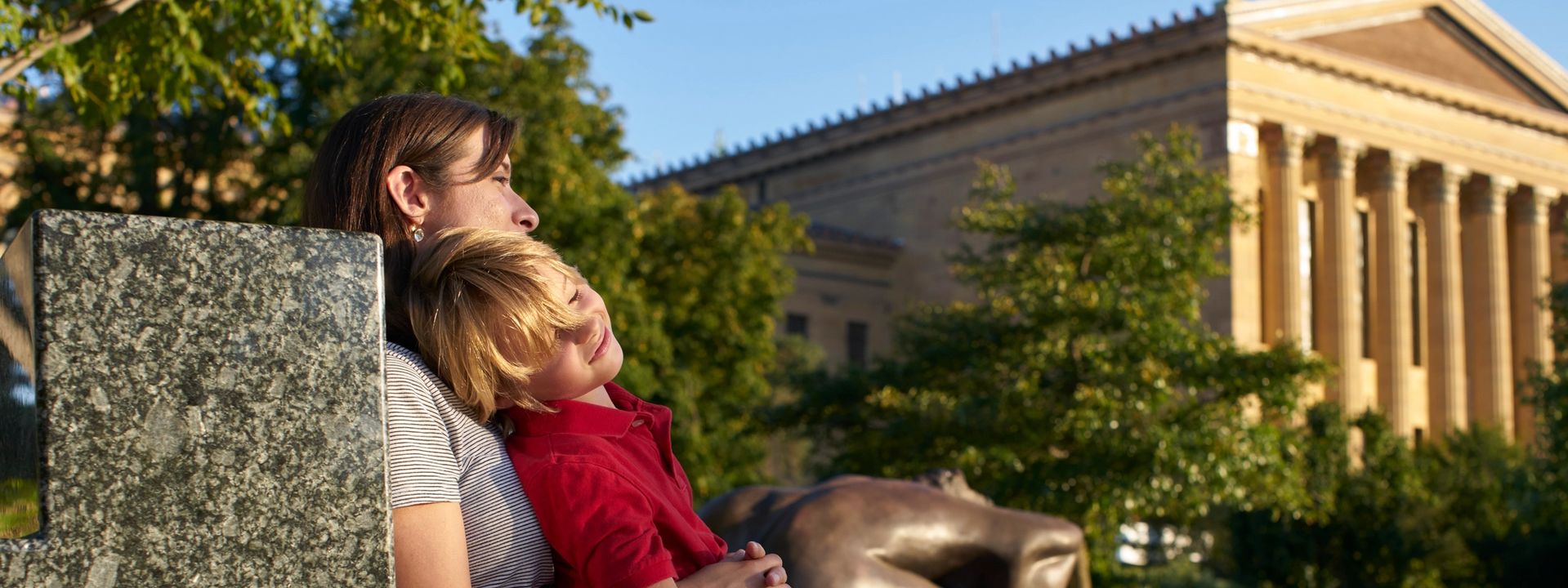 Child sitting on their mother&apos;s lap in front of the museum
