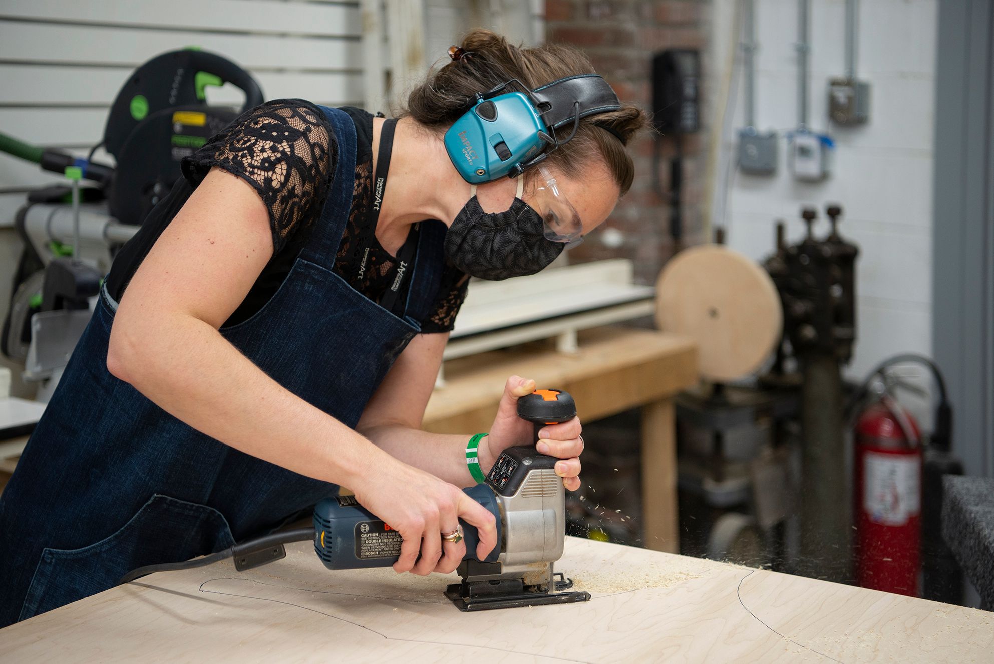 A conservator using a power tool to cut a plank of wood