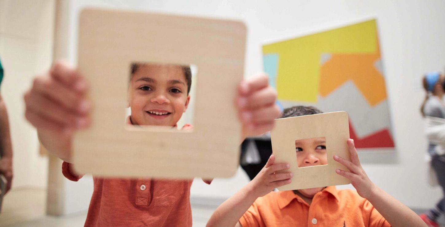 Two children playing with wooden frames and smiling at the camera.