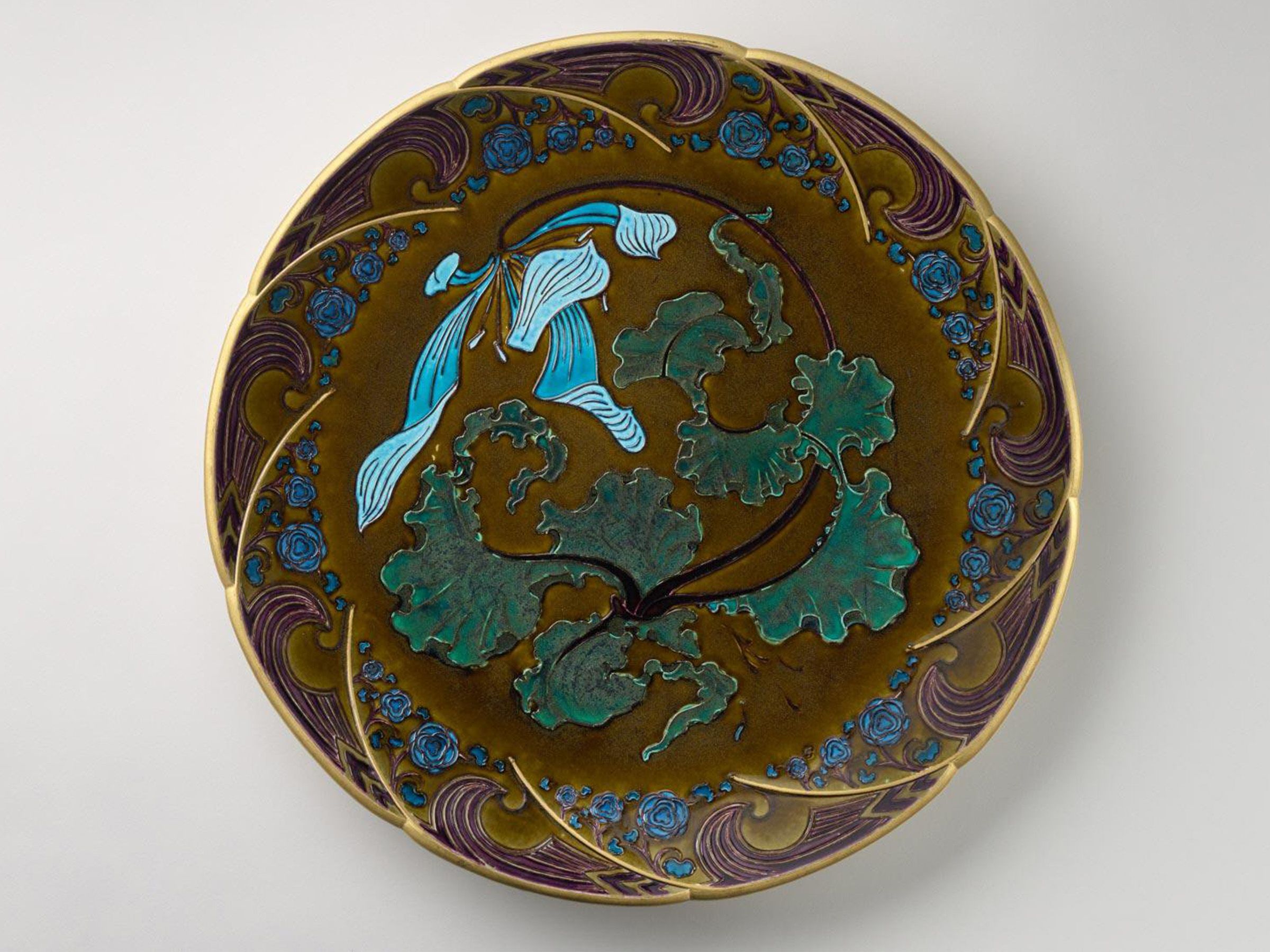 A ceramic lobed shape dish with a breaking waves pattern on the border with a blue flower and cabbage leaves at the center.