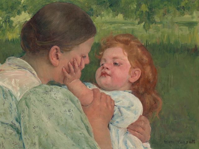 A mother and child looking at each other in a field.