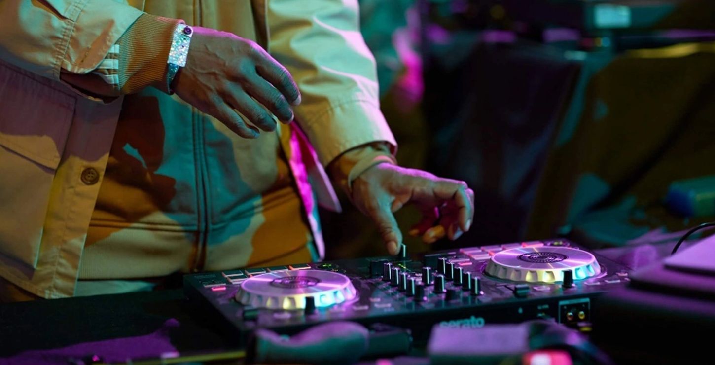 A close up photograph of a a DJ's hands working a mixer at a party.