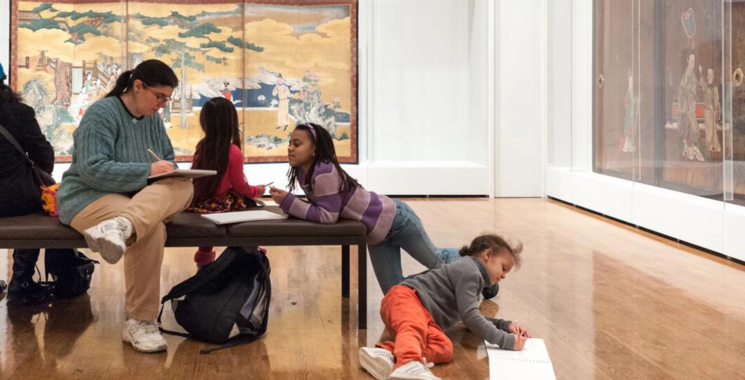 Three children and two adults observing and taking notes in an exhibit.