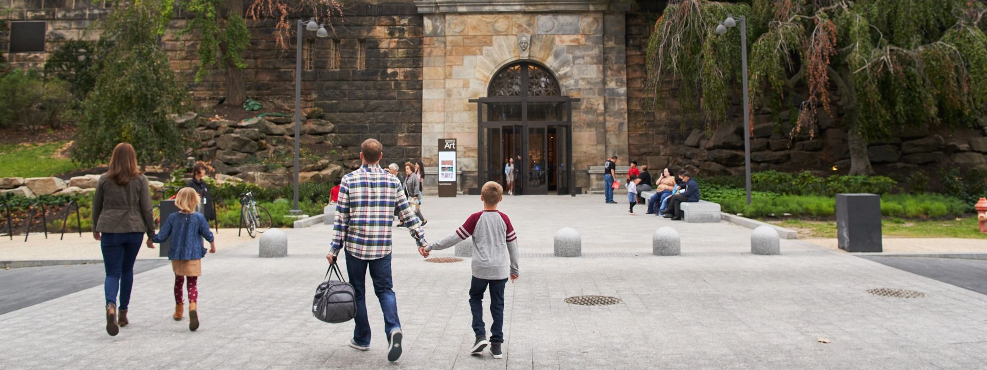 An adult and child holding hands walking up to the museum