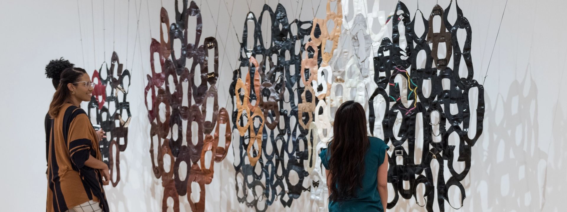 Visitors looking at a hanging installation piece in a gallery