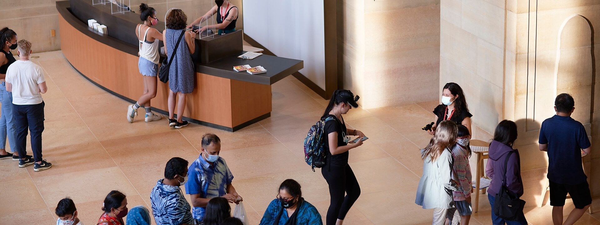 Masked visitors in lobby purchasing admission and getting their tickets scanned by museum staff