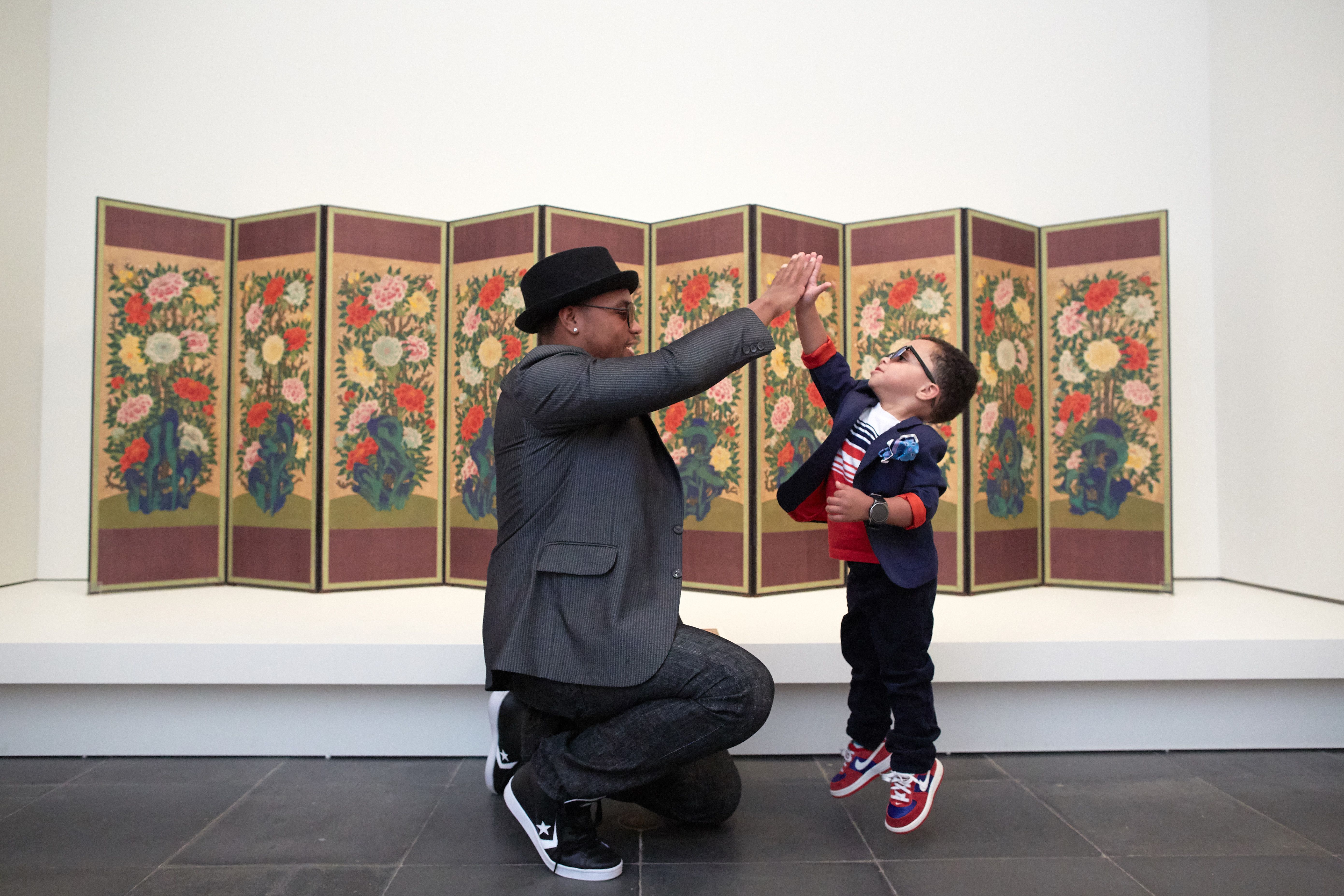 Adult and child high fiving in front of an artwork