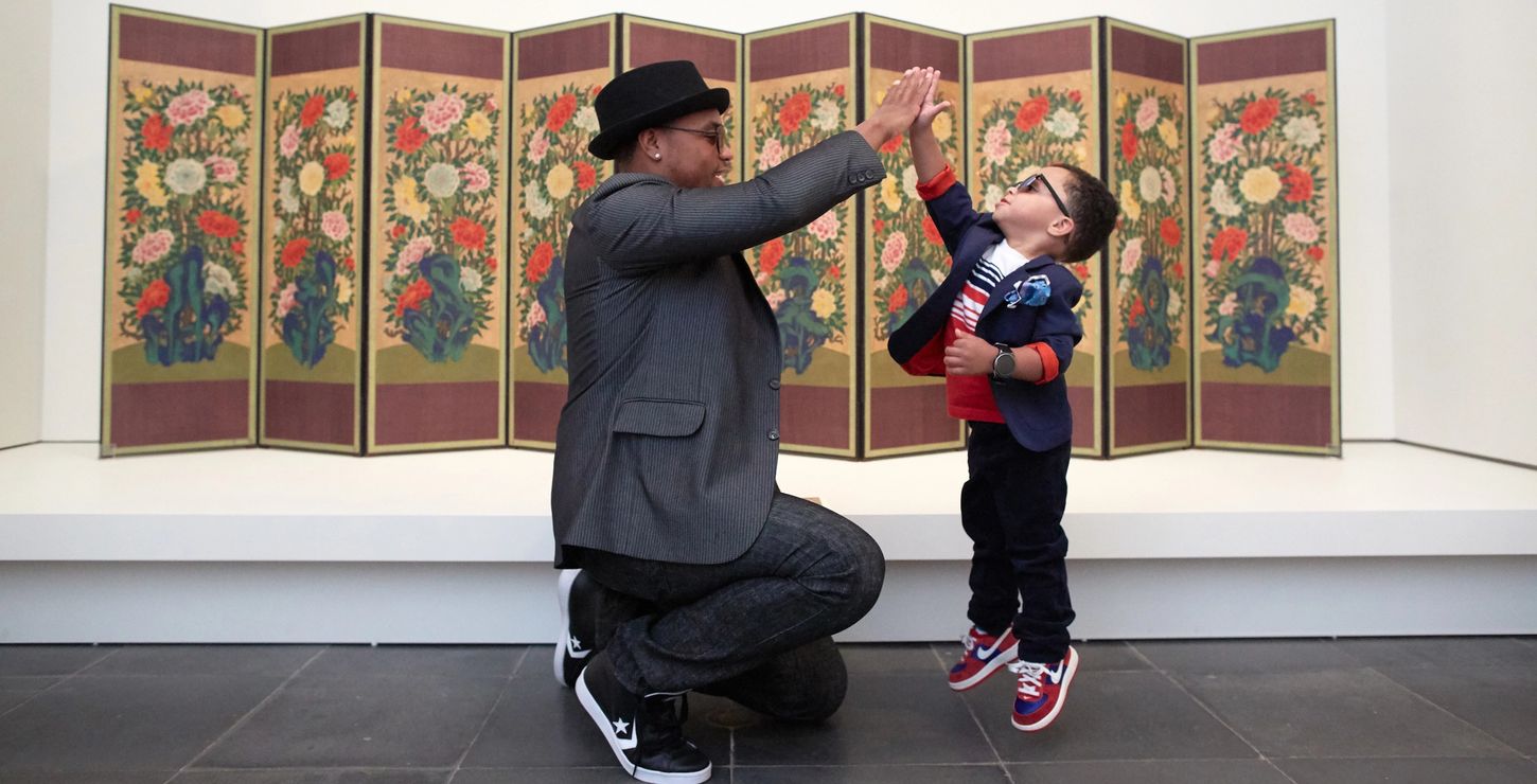Adult and child high fiving in front of an artwork