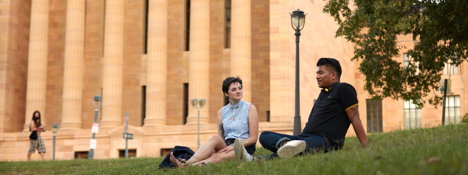 Two visitors sitting on the grass in front of museum