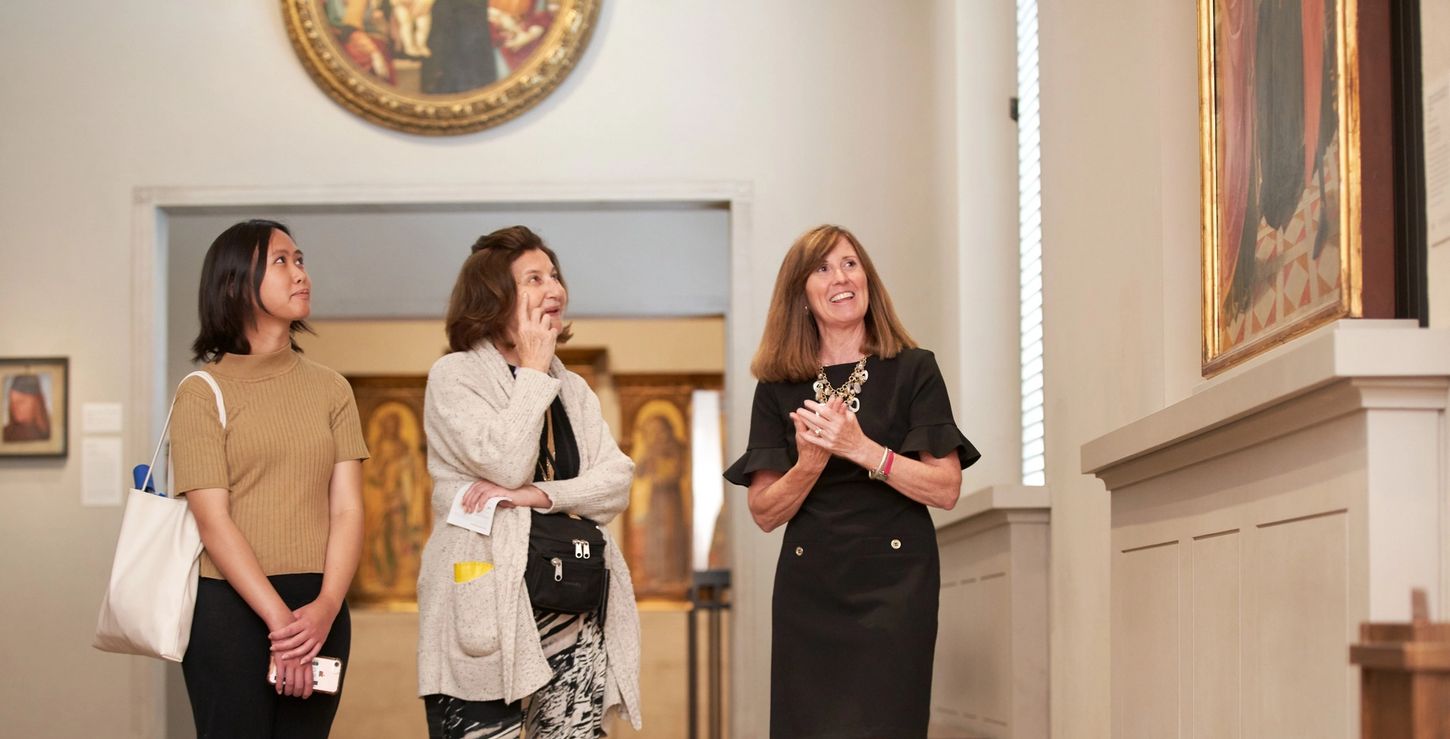 A museum guide and two visitors taking a tour in the galleries