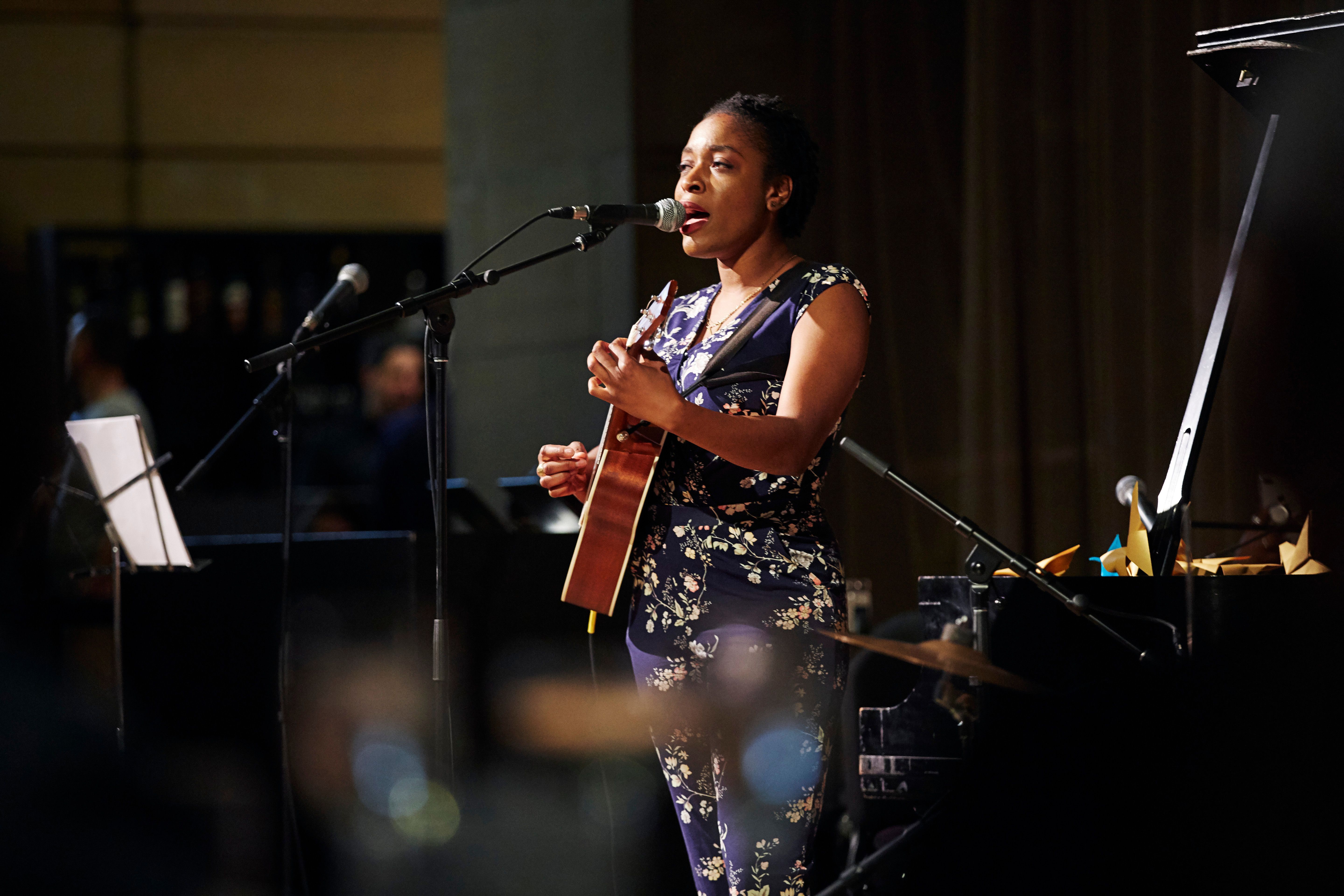 Performer playing guitar and singing on stage