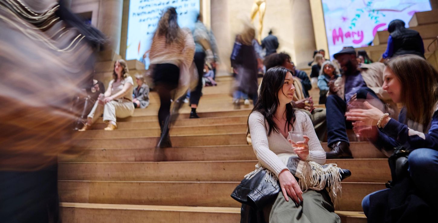 Visitors sitting and talking in the Great Stair Hall with drinks.