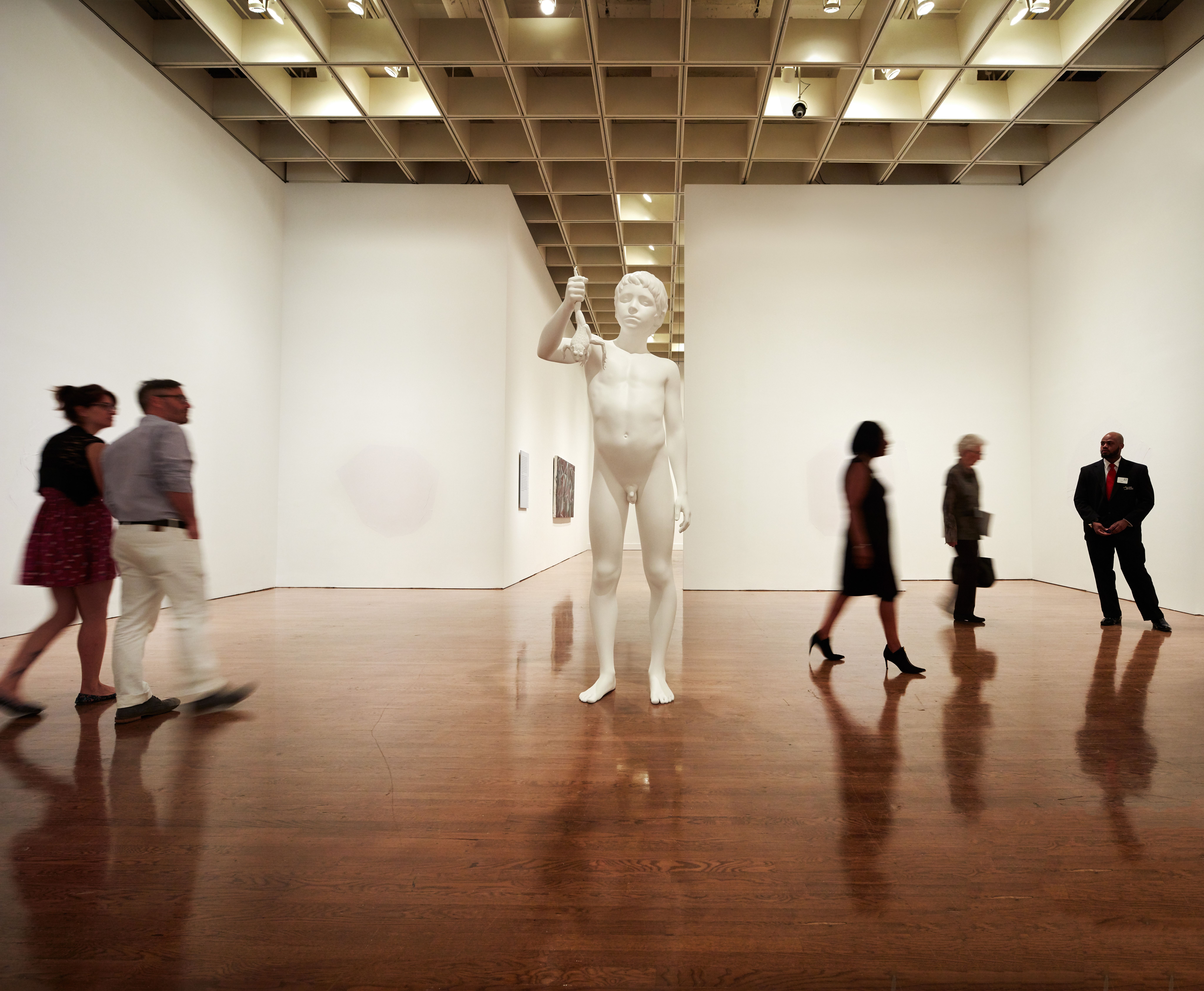 People walking around a large statue in a gallery