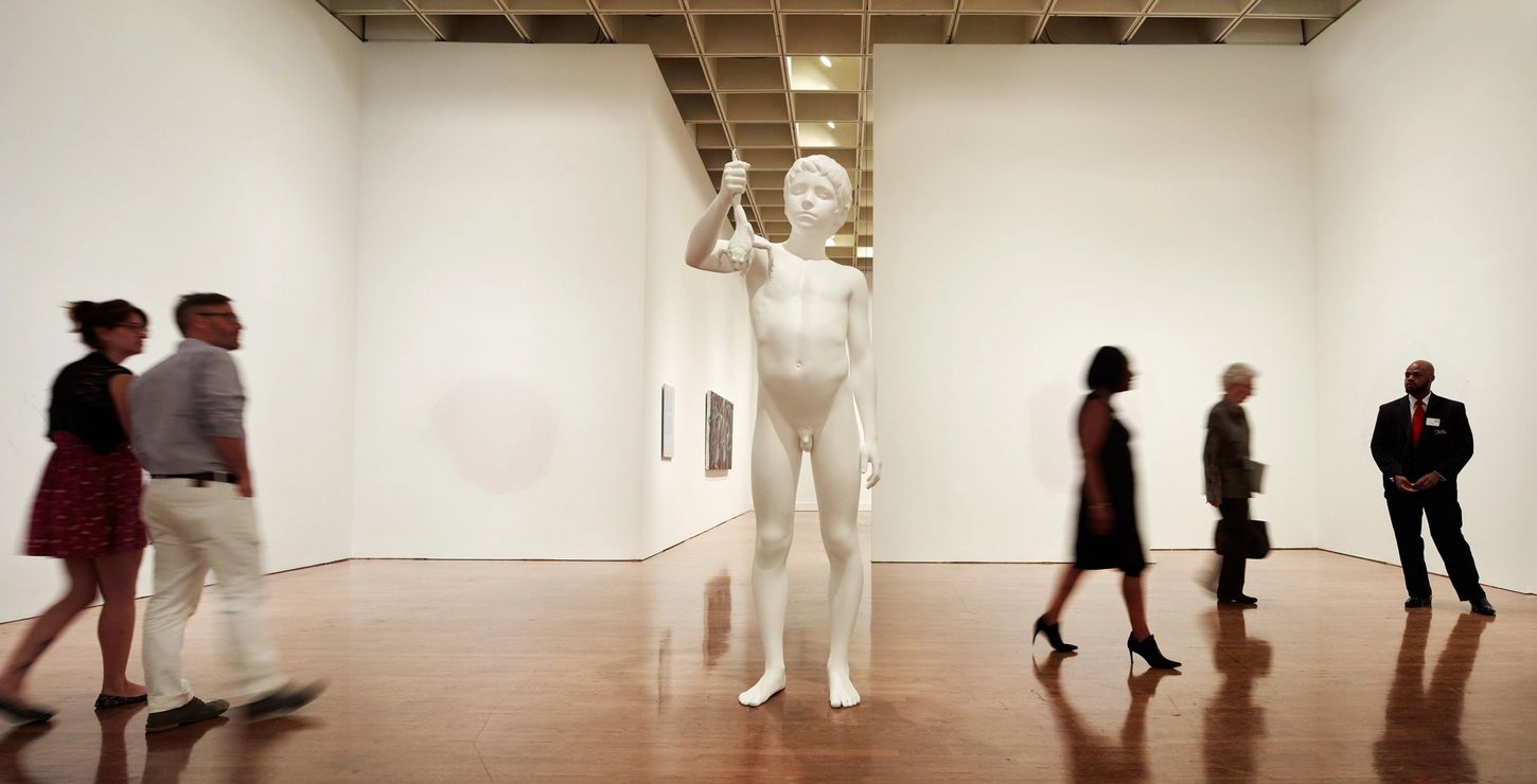 People walking around a large statue in a gallery