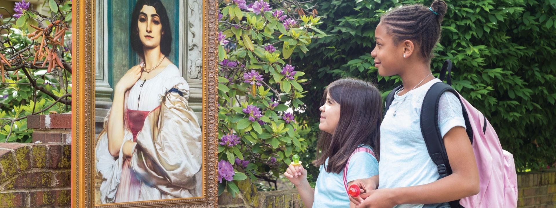 Two children looking at a painting placed outside