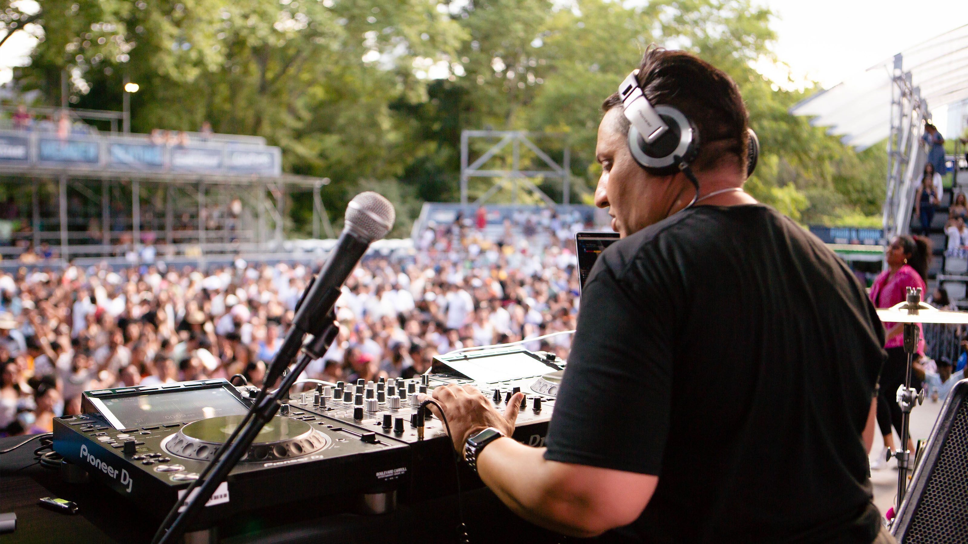 A DJ playing songs in front of a large crowd.
