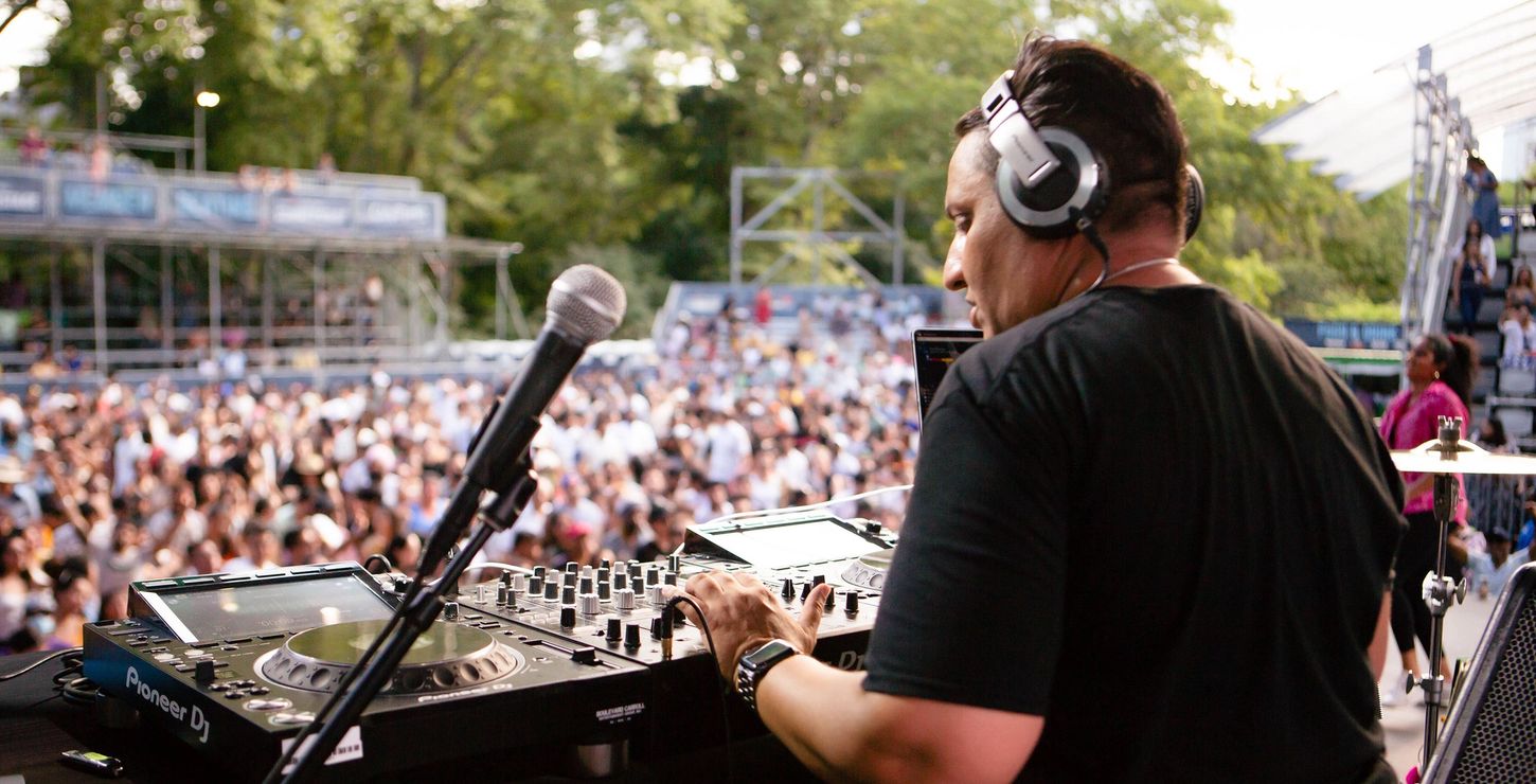 A DJ playing songs in front of a large crowd.