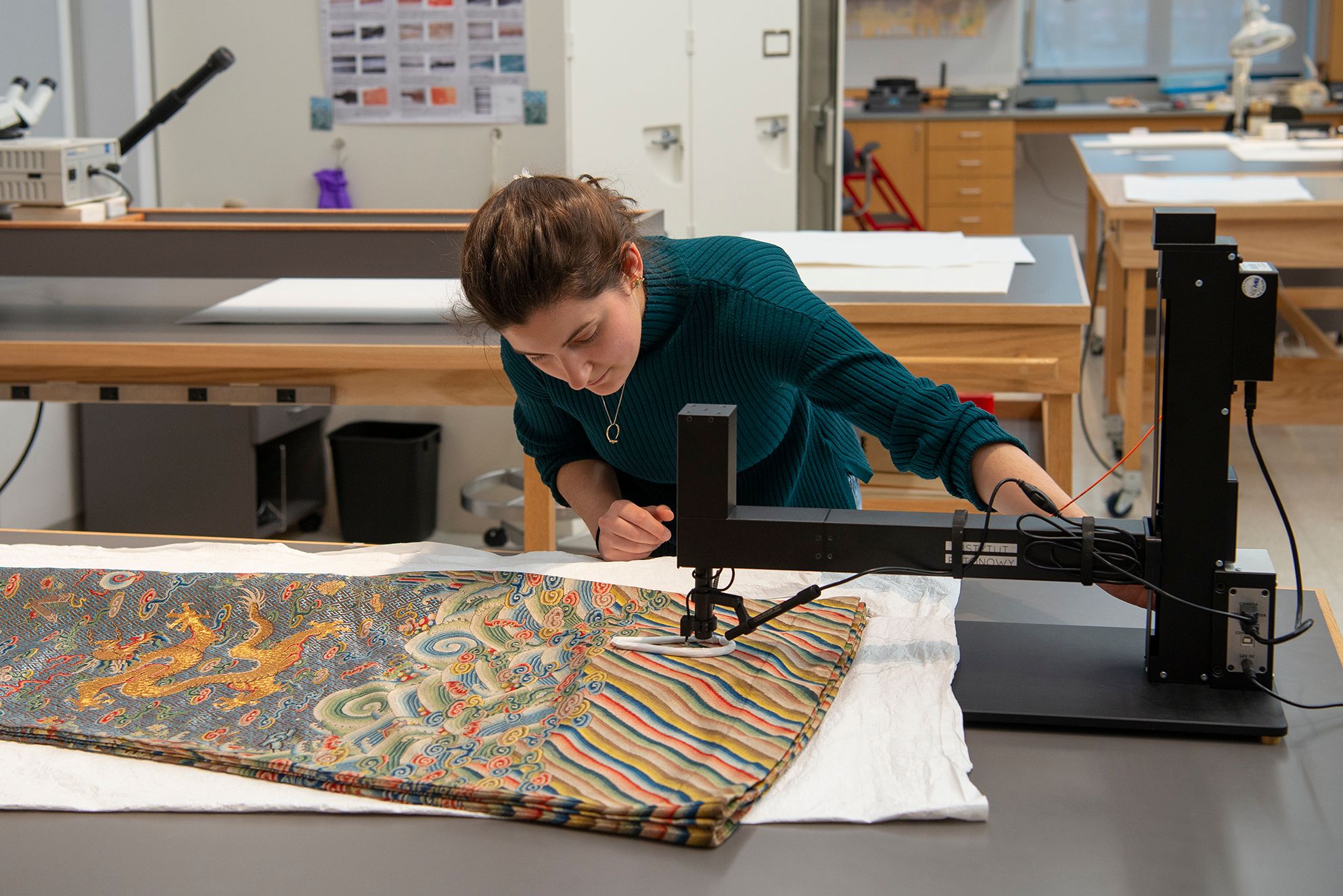 A conservator inspecting and handling the Chinese Dragon Robe Opera Costume