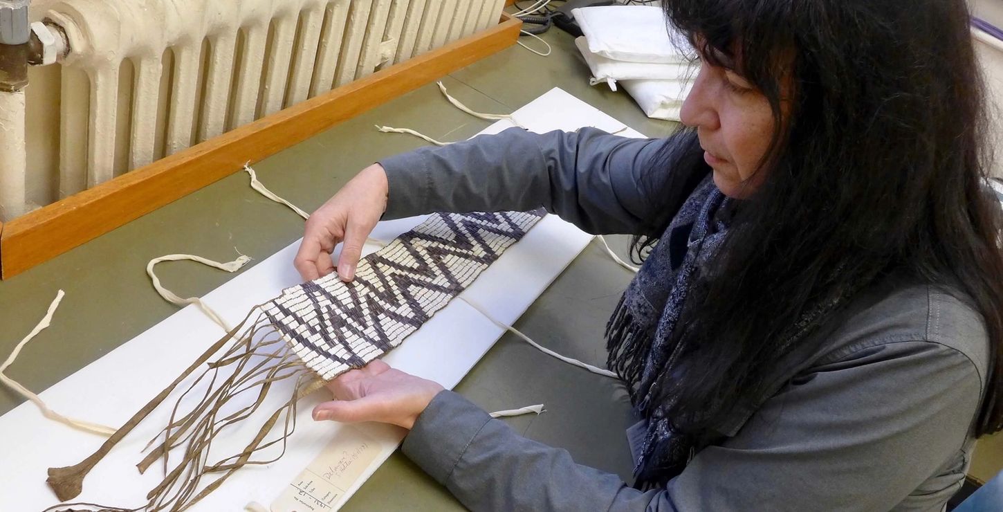 Archivist Margaret Bruchac examines a zigzag wampum belt with an attached leather pendant.