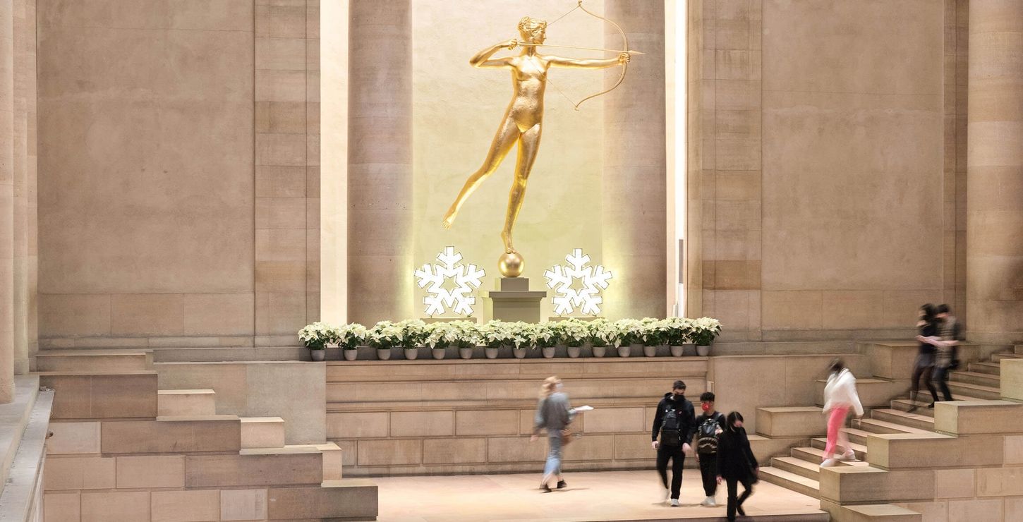 Gilded Diana sculpture with white flowers and holiday star lights in the Great Stair Hall