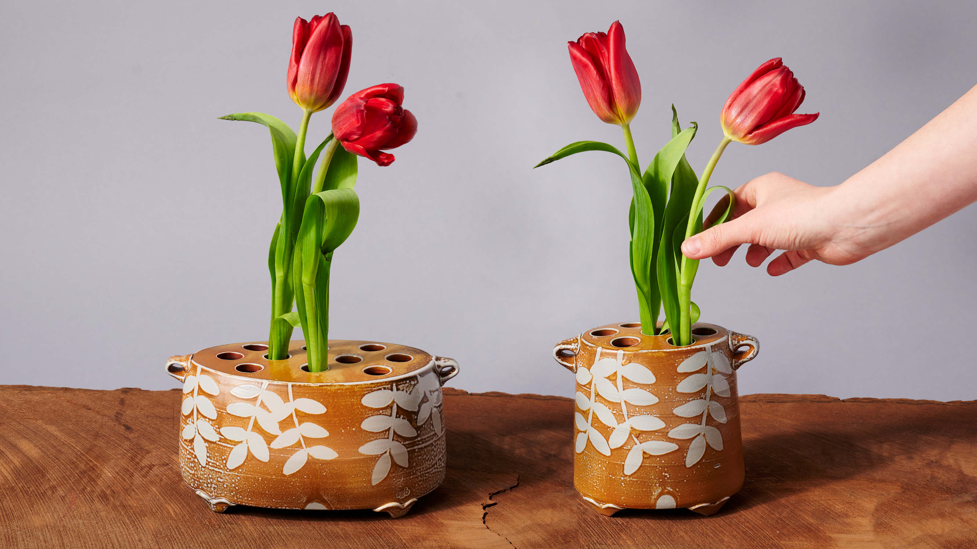 Two vases filled with red tulips on a table.