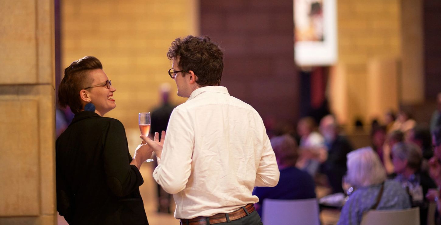 Two people drinking and talking at a party