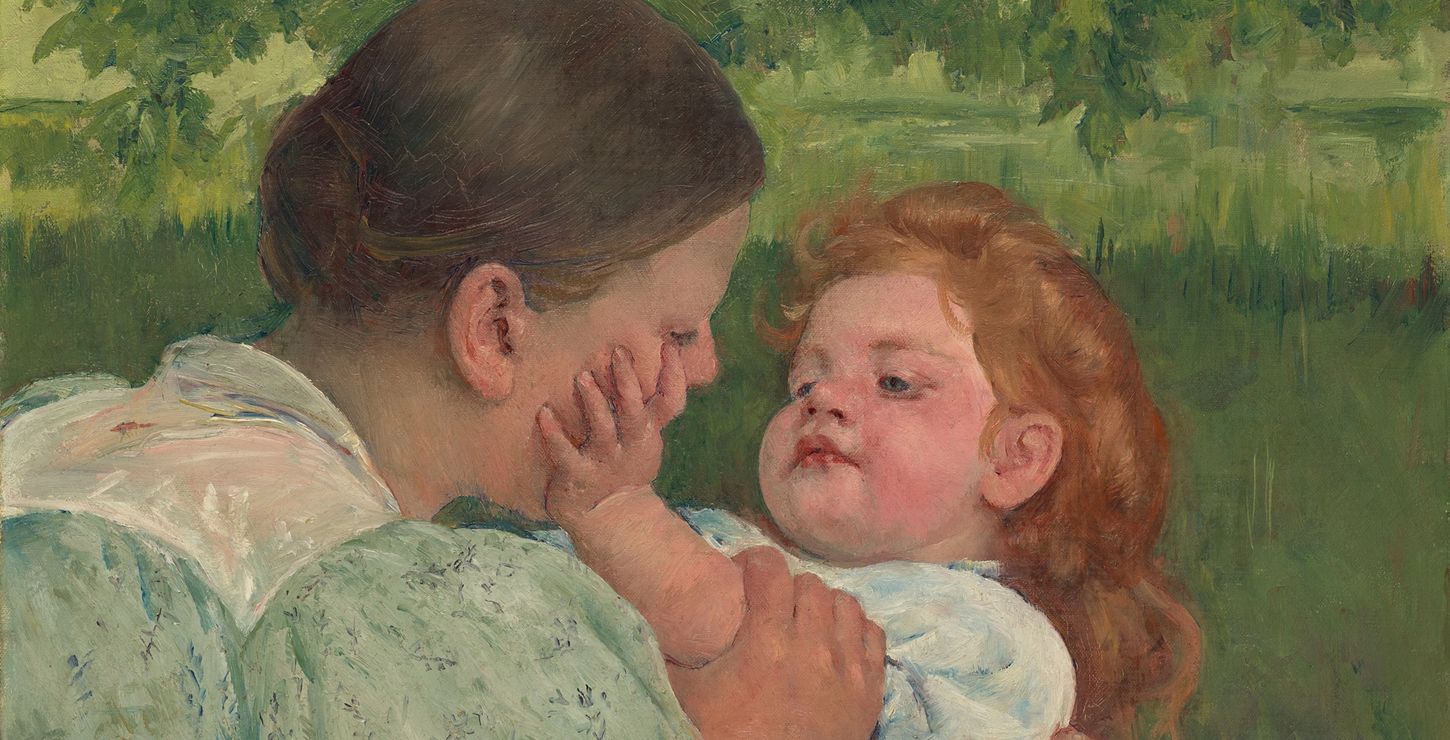 A mother and child looking at each other in a field.