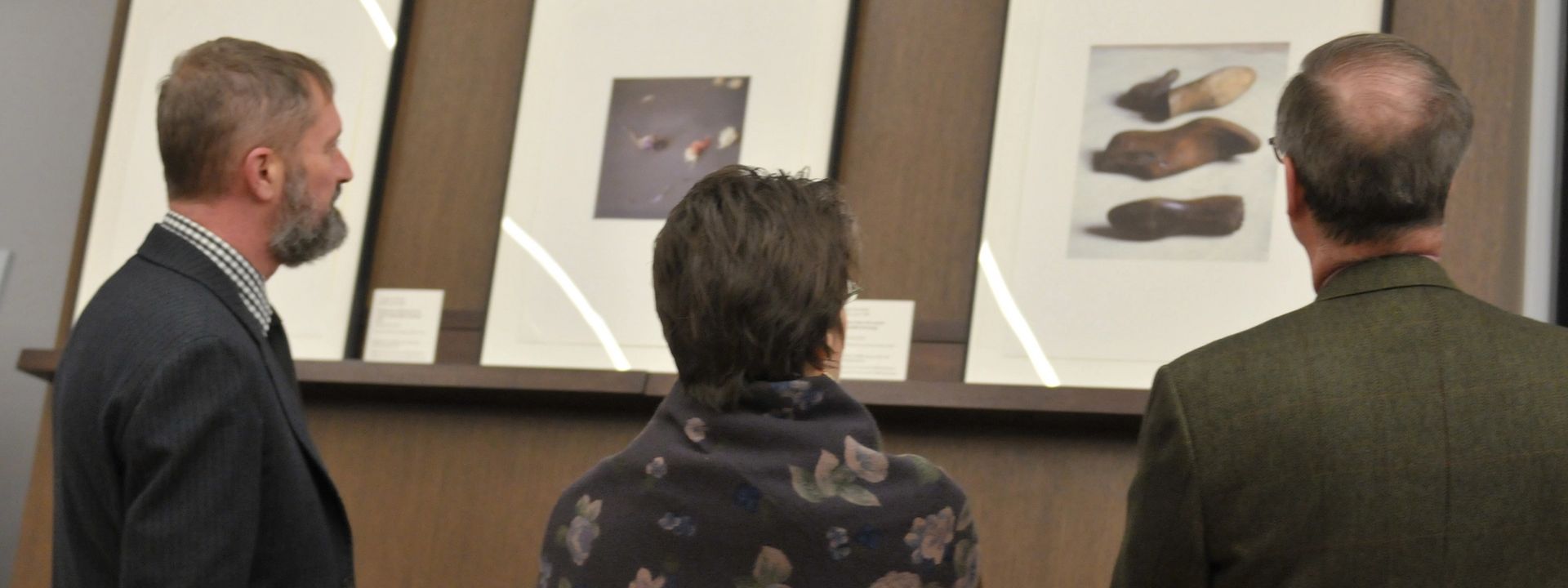 The backs of three people looking at large printed photographs