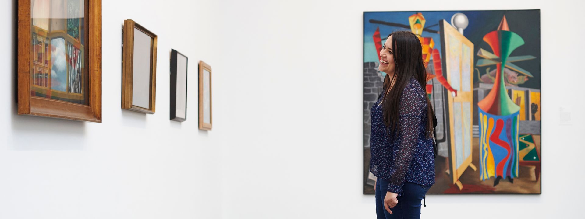 A visitor looking and smiling at a painting on the wall