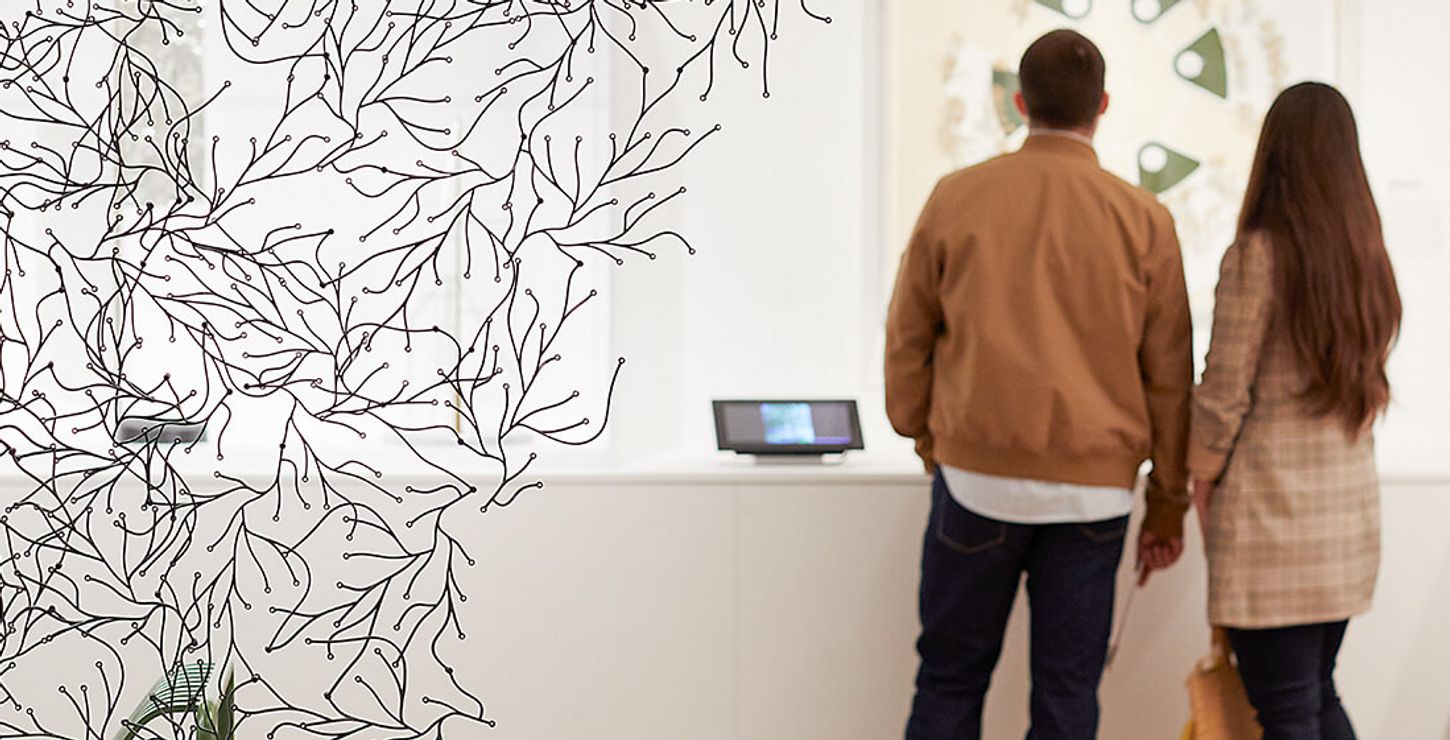 Two visitors walking around a gallery space with white walls and a contemporary installation.
