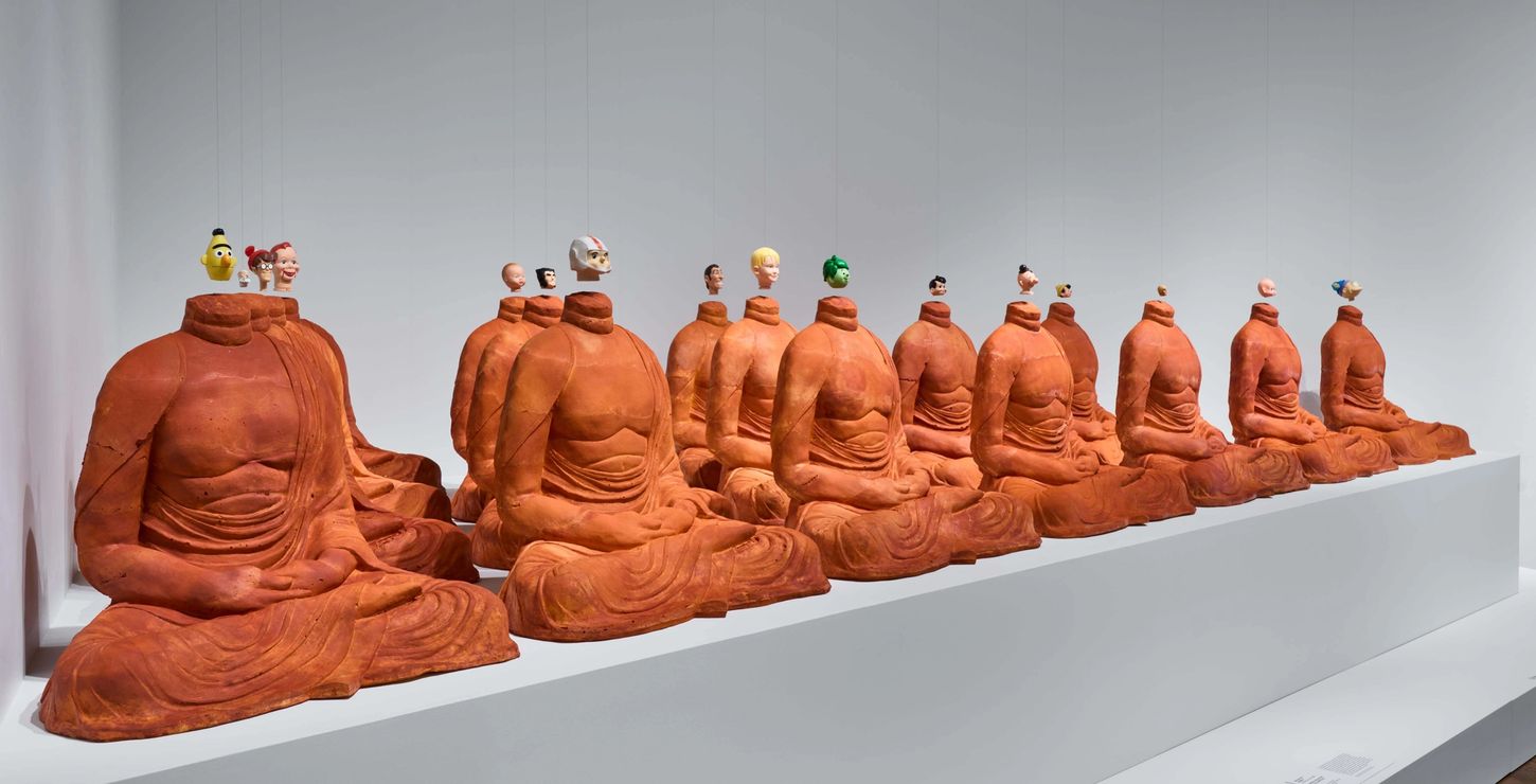 Statues of headless Buddhas with doll heads suspended above the necks.