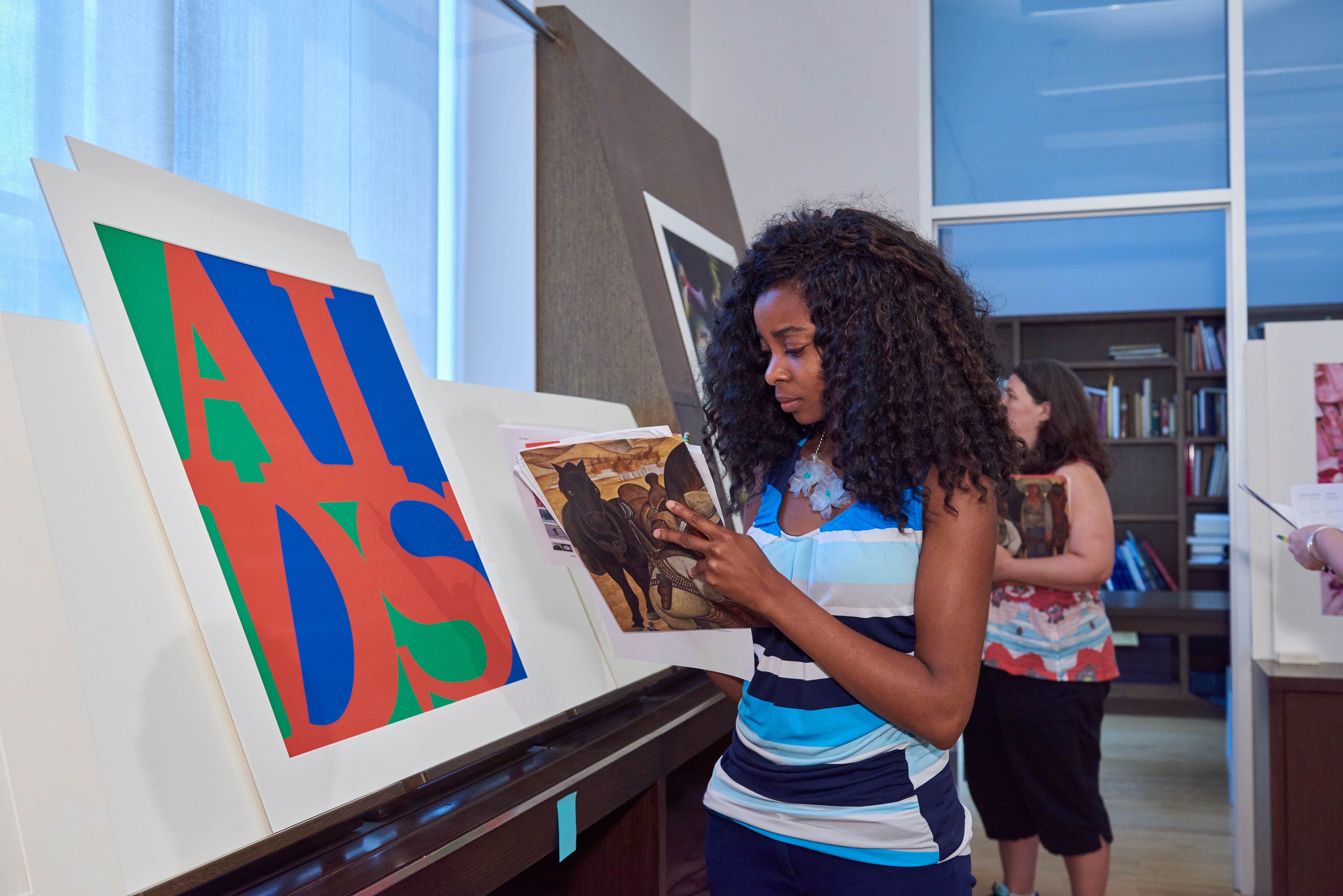 A woman taking notes while standing in front of a large printed artwork