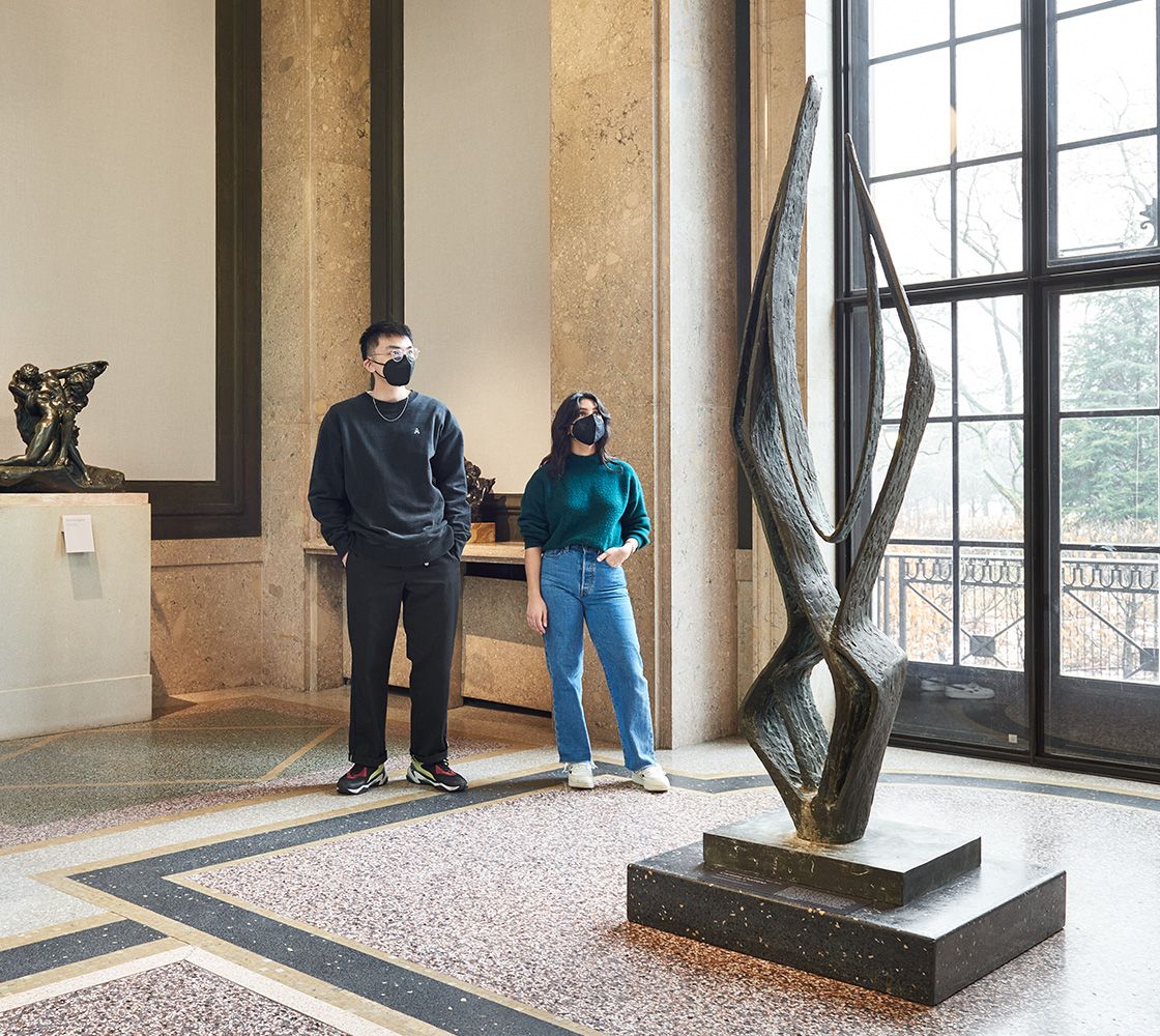 Two people standing in front of a sculpture