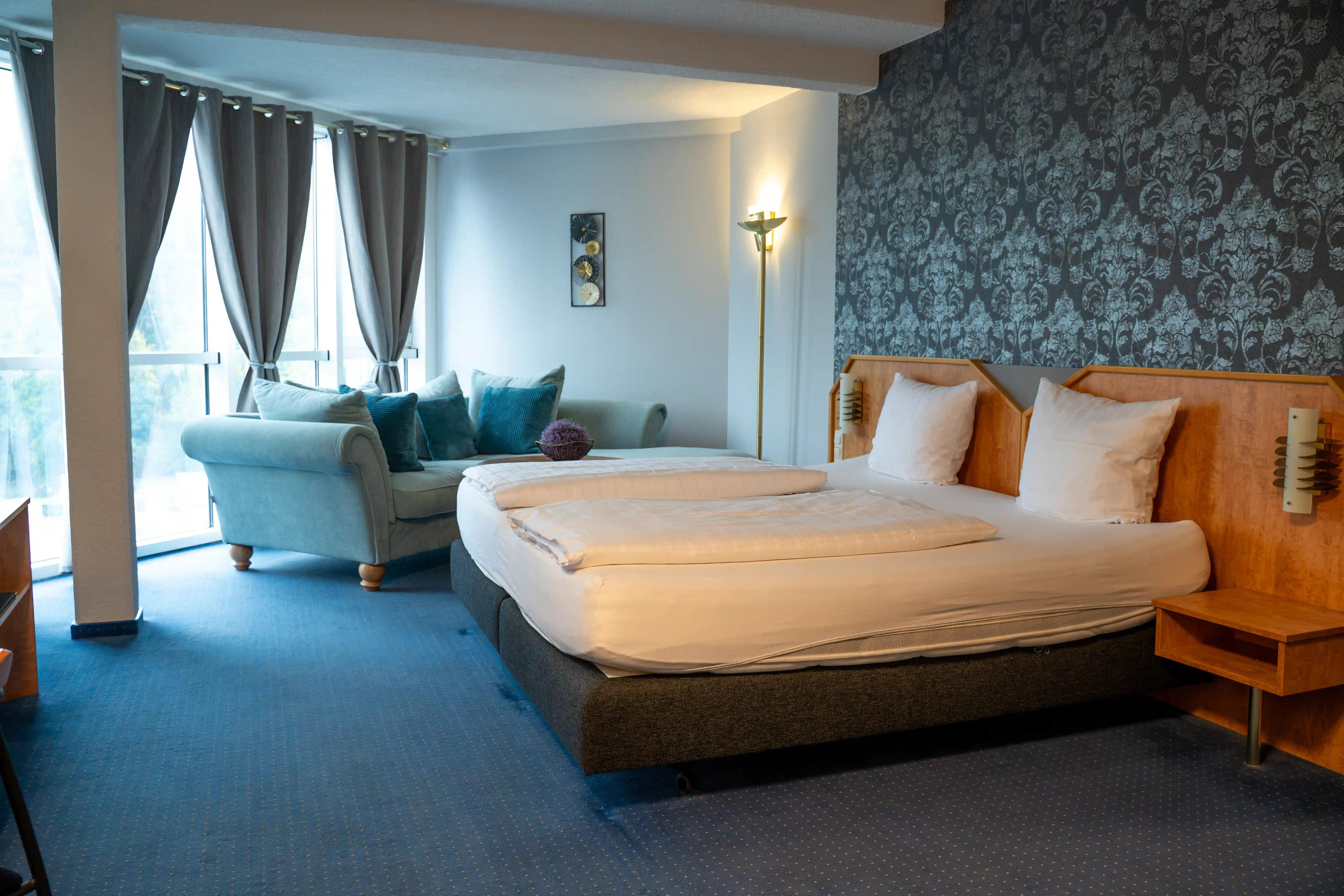 Großzügiges Zimmer mit Doppelbett, Sitzecke und Fensterfront im Hotel Saar Galerie