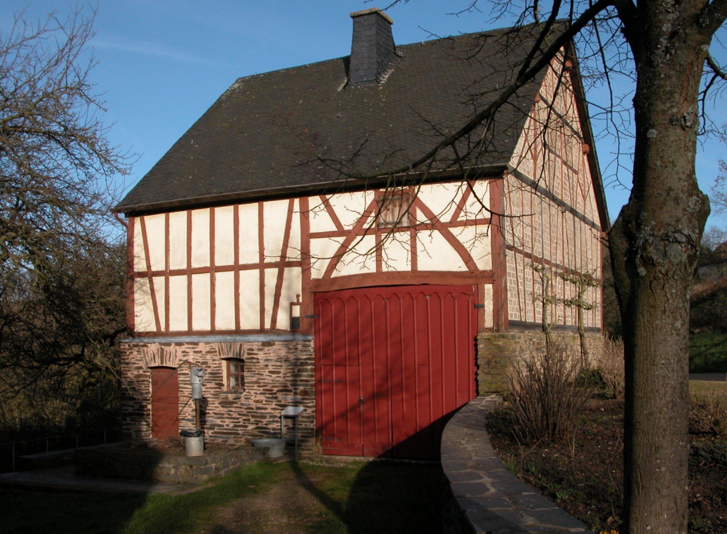 Fachwerk-Stallscheune mit rotem Tor im Freilichtmuseum Roscheider Hof