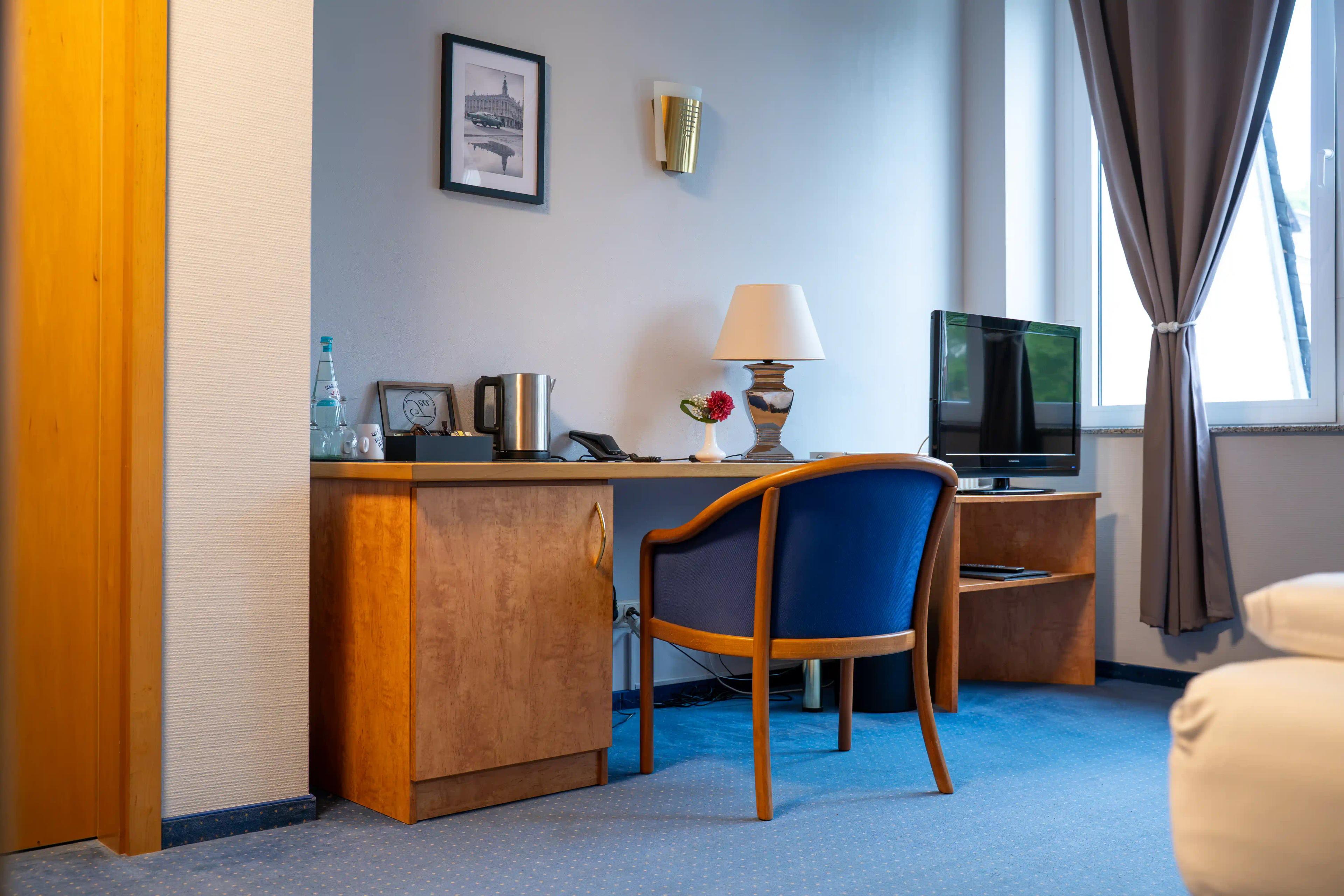 Schreibtisch mit Stuhl, Fernseher und Fenster im Standard-Doppelzimmer