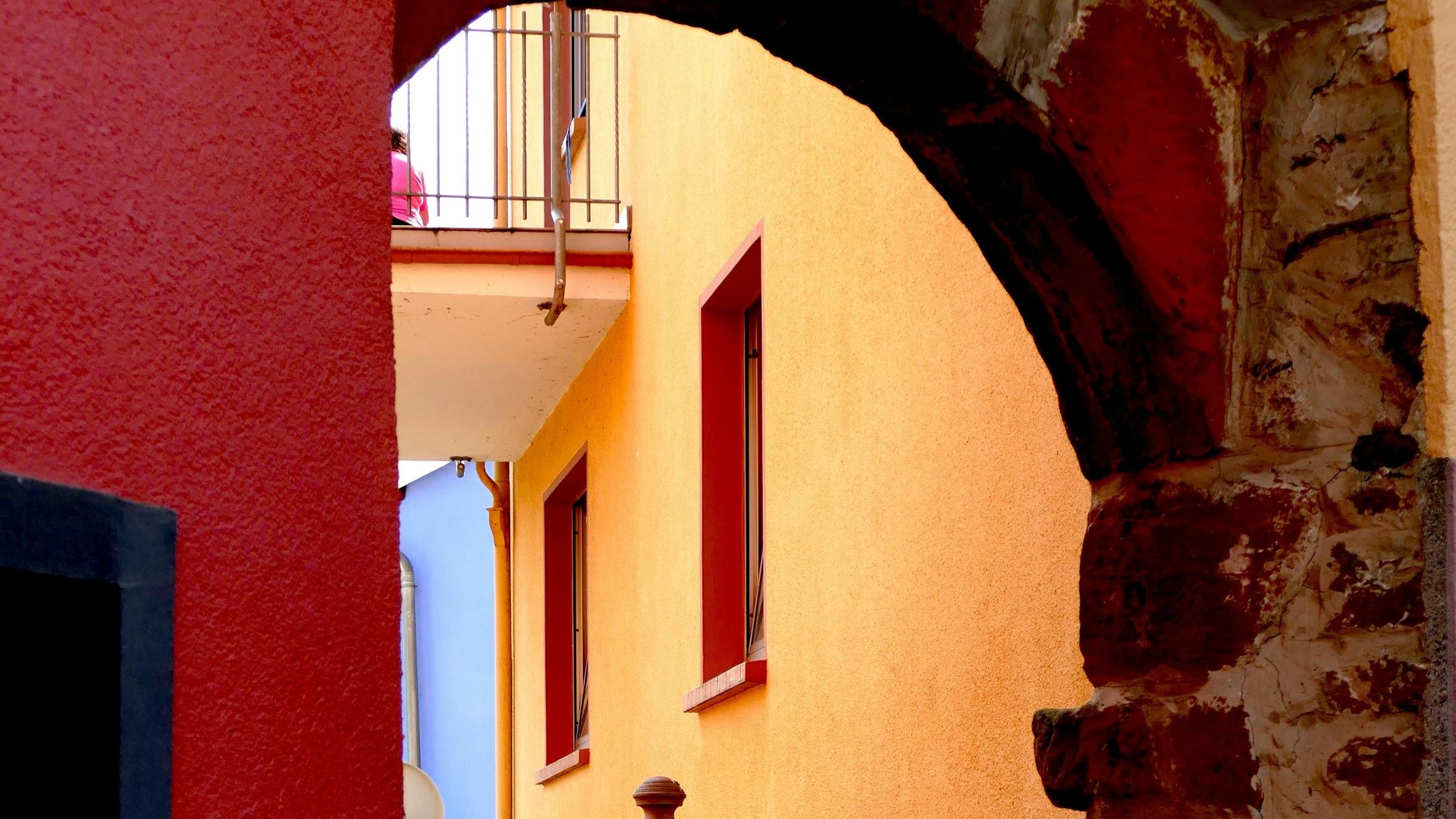 Alter Torbogen aus Sandstein vor sonnigen, bunten Häusern in der Saarburger Altstadt